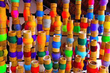 Closeup of group many asian natural vibrant multicolored bamboo sewing thread spools in rows - Thailand