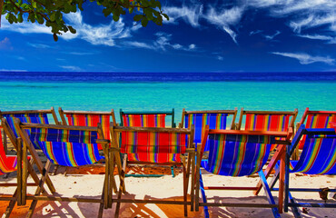Naklejka na ściany i meble Group of isolated empty deck chairs on beach of Tropical Island with panoramic view on turquoise water, Ko Phi Phi, Andaman Sea, Thailand