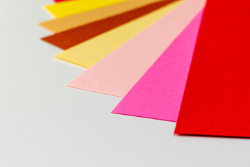 白いテーブルの上に並べられた暖色系のカラフルな紙