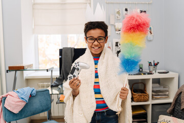 Black boy smiling while posing with joystick and colorful duster © Drobot Dean