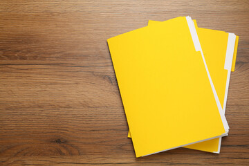 Yellow files with documents on wooden table, top view. Space for text