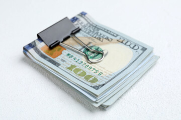 Many dollar banknotes with paper clip on white table, closeup