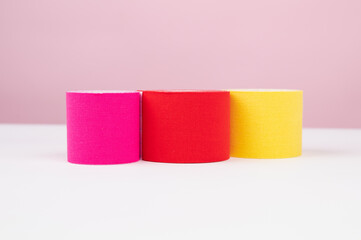 Three pieces of lifting or kinesio tape rolls on pink background with copy space. Alternative medicine concept