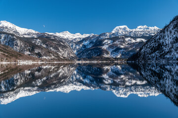 Fototapeta na wymiar Breathtaking view over Grundlsee in Salzkammergut, Ausseerland, snowcaped Mountains reflecting in crystal clear mountain lake, Winter Wonderland in Austria