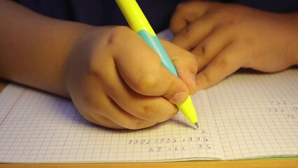 Pupil's hands close-up carefully solve math in a notebook. A schoolboy at the workplace does his job. Education concept, modern school, knowledge acquisition, traditional learning. UHD 4K.