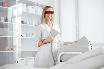 Cheerful woman beautician using modern equipment in beauty salon