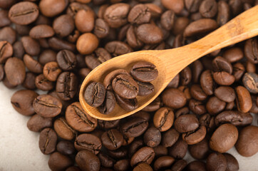 Obraz premium Coffee beans in a wooden spoon on the side of the coffee beans. Close-up. Top view