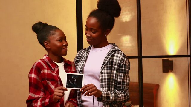 african american two happy future mothers sonogram image at home in evening