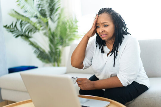 Photo of pretty black woman using laptop at home sofa and buy something on the web look like worry about this