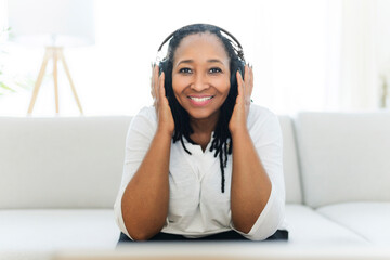 Woman with headphones on couch and listening to music