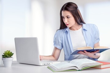 Concentrated young woman sitting in the comfortable office, studying or working on computer