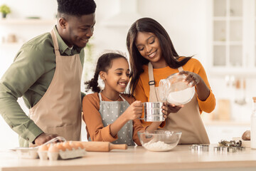 African American Family Baking Cookies Using Flour Sifter In Kitchen