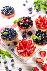 Fresh berries and ricotta cheese in tartletes. Summer dessert, healthy breakfast or snack, open sandwiches with strawberry, blueberries, blackberries.