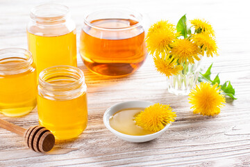 Dandelions honey syrup in the glass jar made in springtime on white wooden table. Homemade sweet food.