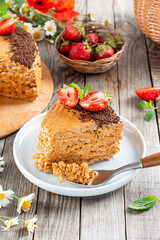 An appetizing piece of waffle cake with condensed milk, chocolate and strawberries on a wooden table. Close up view. Bakery food photography.