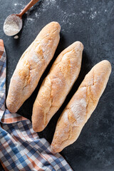 Three crunchy french baguettes on a gray stone surface