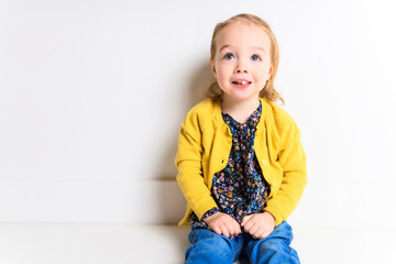 Cute playful baby girl sitting on the floor of a white background