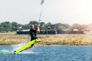 Young adult caucasian fit male person enjoy riding kite surf board in sun uv protection suit on bright sunny day against blue sky at sea or ocean shore. Watersport adrenaline fun adventure acitivity