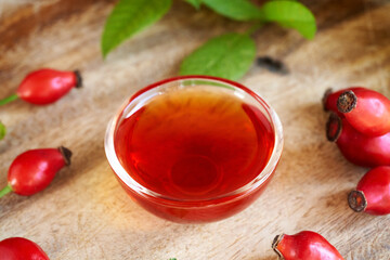 A bowl of rosehip seed oil with fresh rose hips