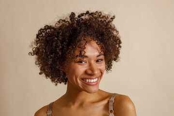 Multiracial woman with fluffy hairdo looking at camera in studio