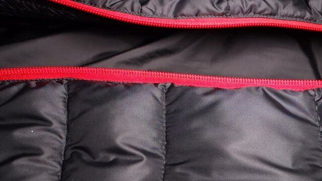 Adding one half of the red zipper to the other on a black winter windbreaker