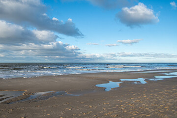 Wolken, Wellen und Pfützen am Strand der Nordsee