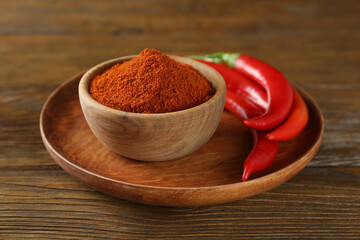 Paprika powder and fresh chili peppers on wooden table