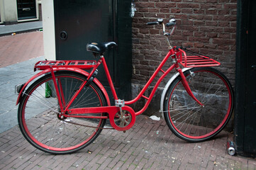 Fototapeta na wymiar A red bicycle parked on a street in the center of Amsterdam, Netherlands.