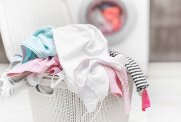 Laundry in a basket for dirty clothes on the background of a washing machine.