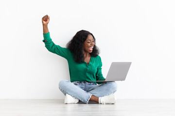 Emotional black woman trading on Internet, using notebook