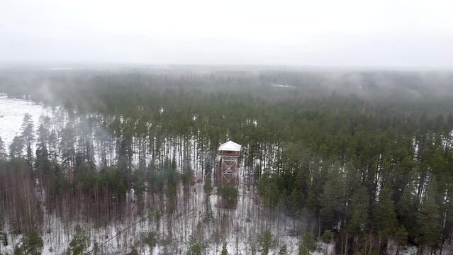 Turning aerial drone view through smoke and fog on Valgesoo viewing tower in Estonia during winter