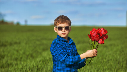 Portrait of a boy with a bouquet of red tulips outdoors