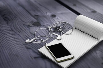 Bible, journal, cell phone on a dark wood desk