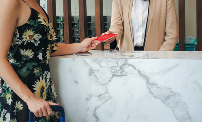 Young travelers talking and check-in register information with woman receptionist worker standing in counter hotel reception counter desk at lobby modern hotel..