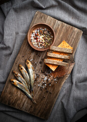 Cold smoked fish on an old wooden board with spices.