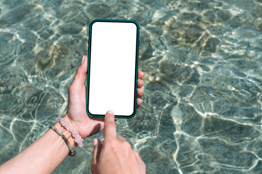 Finger in front of a mockup of a smartphone in a girl's hand. Against the backdrop of clear water around the pool.