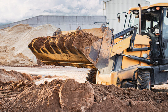The excavator loader works with a bucket for transporting sand at a construction site. Professional construction equipment for earthworks.