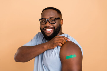 Portrait of attractive cheerful guy showing shoulder plaster anti mers cov isolated over beige pastel color background