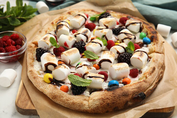 Tasty sweet pizza with berries, marshmallows and candies on table, closeup