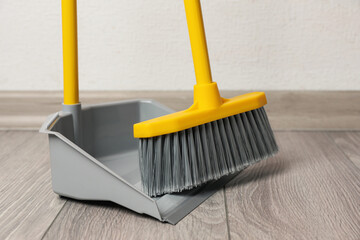 Plastic broom with dustpan on wooden floor indoors - obrazy, fototapety, plakaty