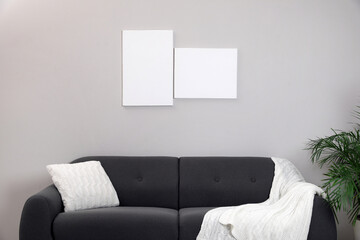 Blank canvas on wall over comfortable sofa indoors. Space for design