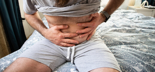 man in bedroom suffering from abdominal pain