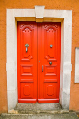 Red door of an old house in the village of Roussillon in the Luberon valley in Provence, France