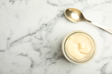 Jar of delicious mayonnaise and spoon on white marble table, flat lay. Space for text