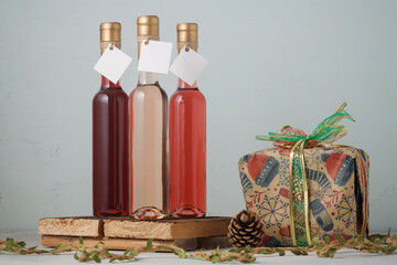 Christmas wine and present box. Three bottles of red and pink wine, no brand, mock up on wooden background. Copy space
