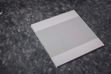 White photobook or family album with hard cover without any design on grey painted background. Mock...