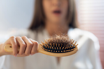 Hairloss Concept. Worried Woman Holding Comb Full Of Fallen Hair After Brushing - obrazy, fototapety, plakaty