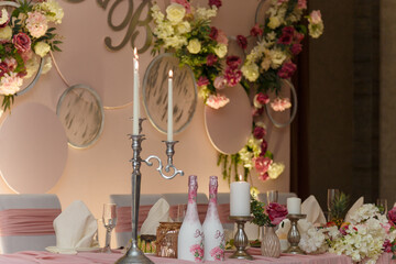 Decorated pink wedding presidium, festive arch, screen for just married, event organization. Beautiful flowers, champagne bottles, candles.