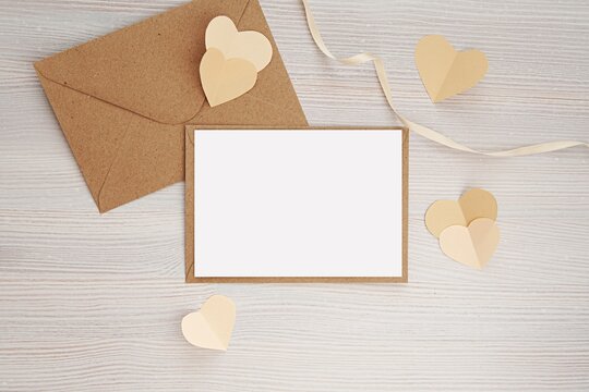Valentines day greeting card mockup with brown envelopes, ribbon and paper hearts, horizontal card mock up, neutral cream colors.