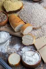wheat baguette on the table with flour and various plant grains